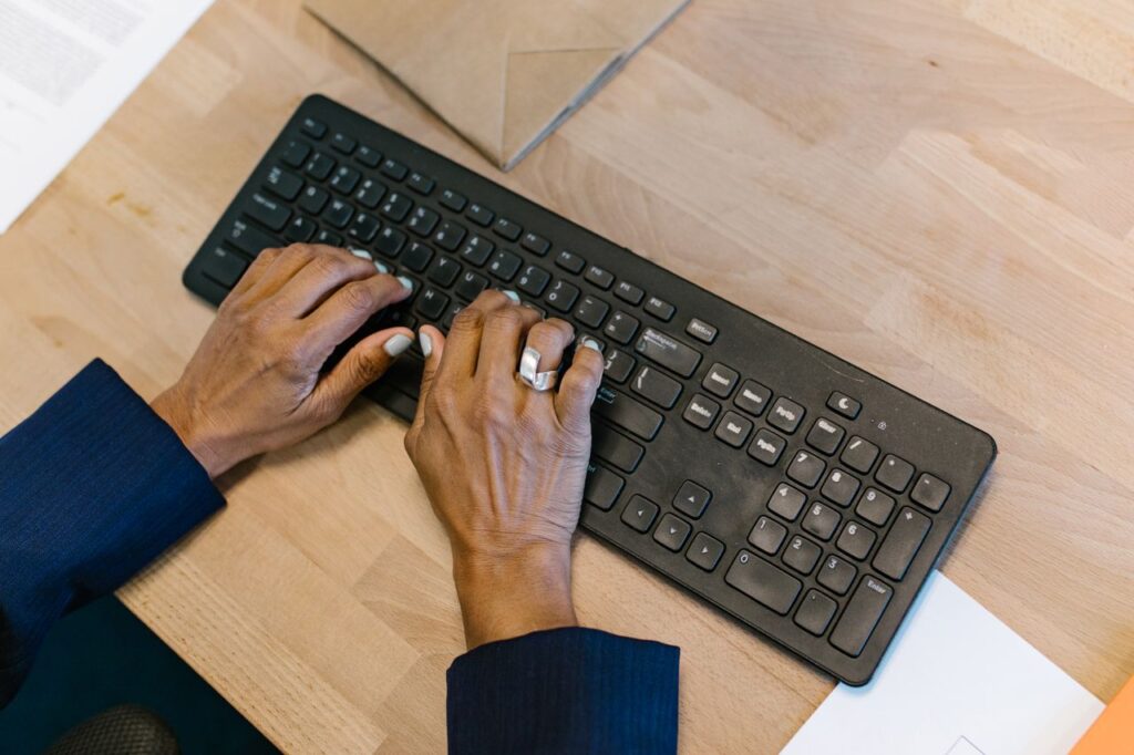 Overhead shot of hands typing on a keyboard in an office setting, highlighting productivity and technology.